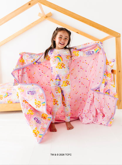 Child playing with a colorful comforter on a wooden frame bed.