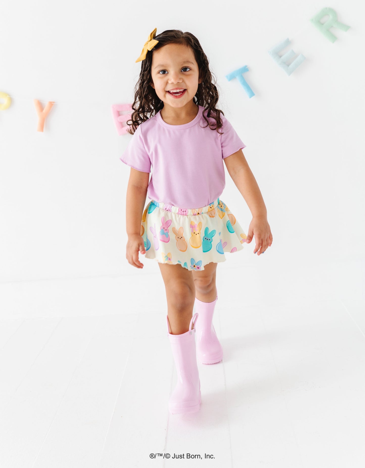 Child wearing a pink shirt and colorful PEEPS® skirt with a white background