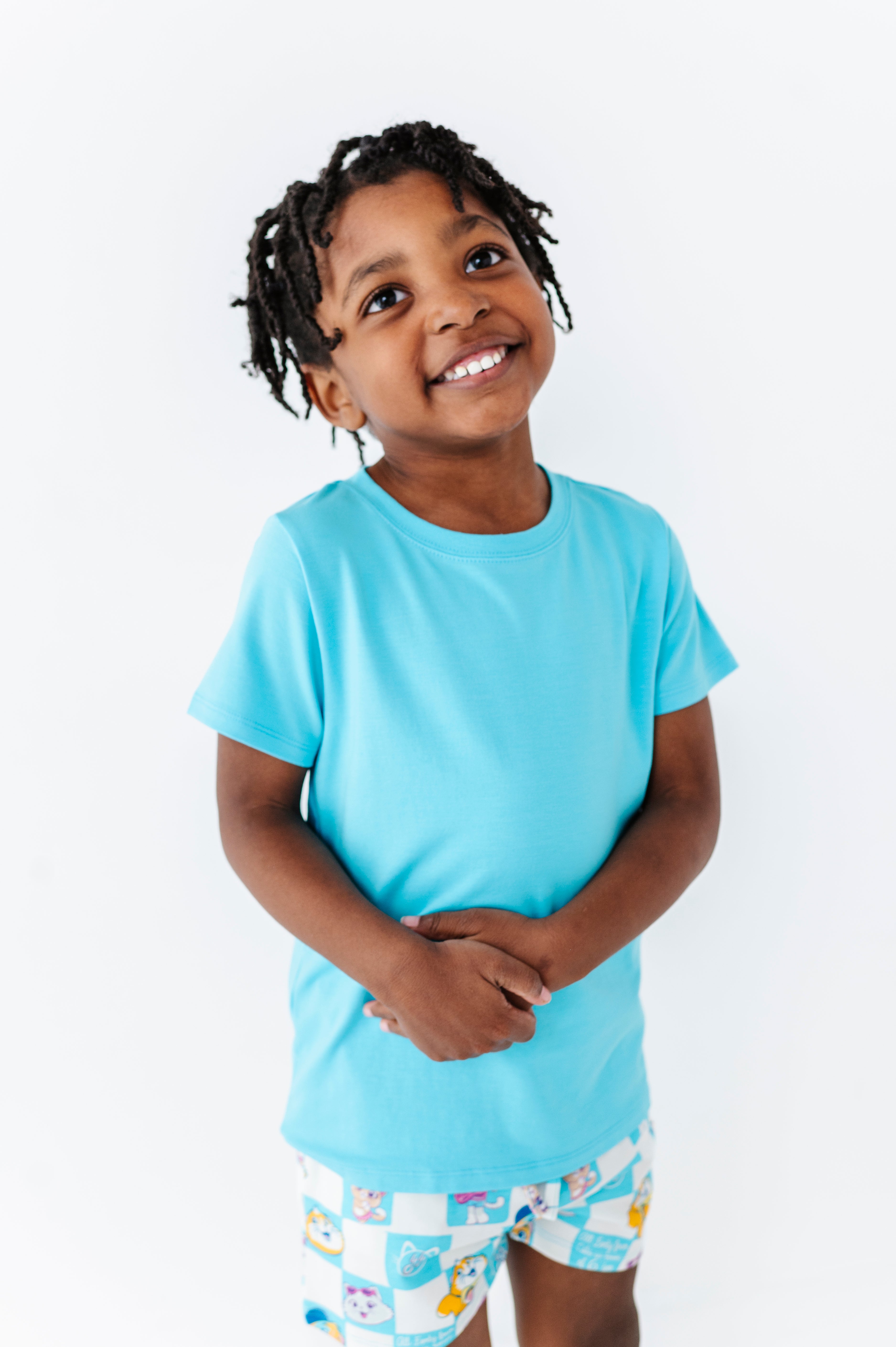 Child wearing a light blue bamboo blent t-shirt and patterned 44 CATS shorts on a white background