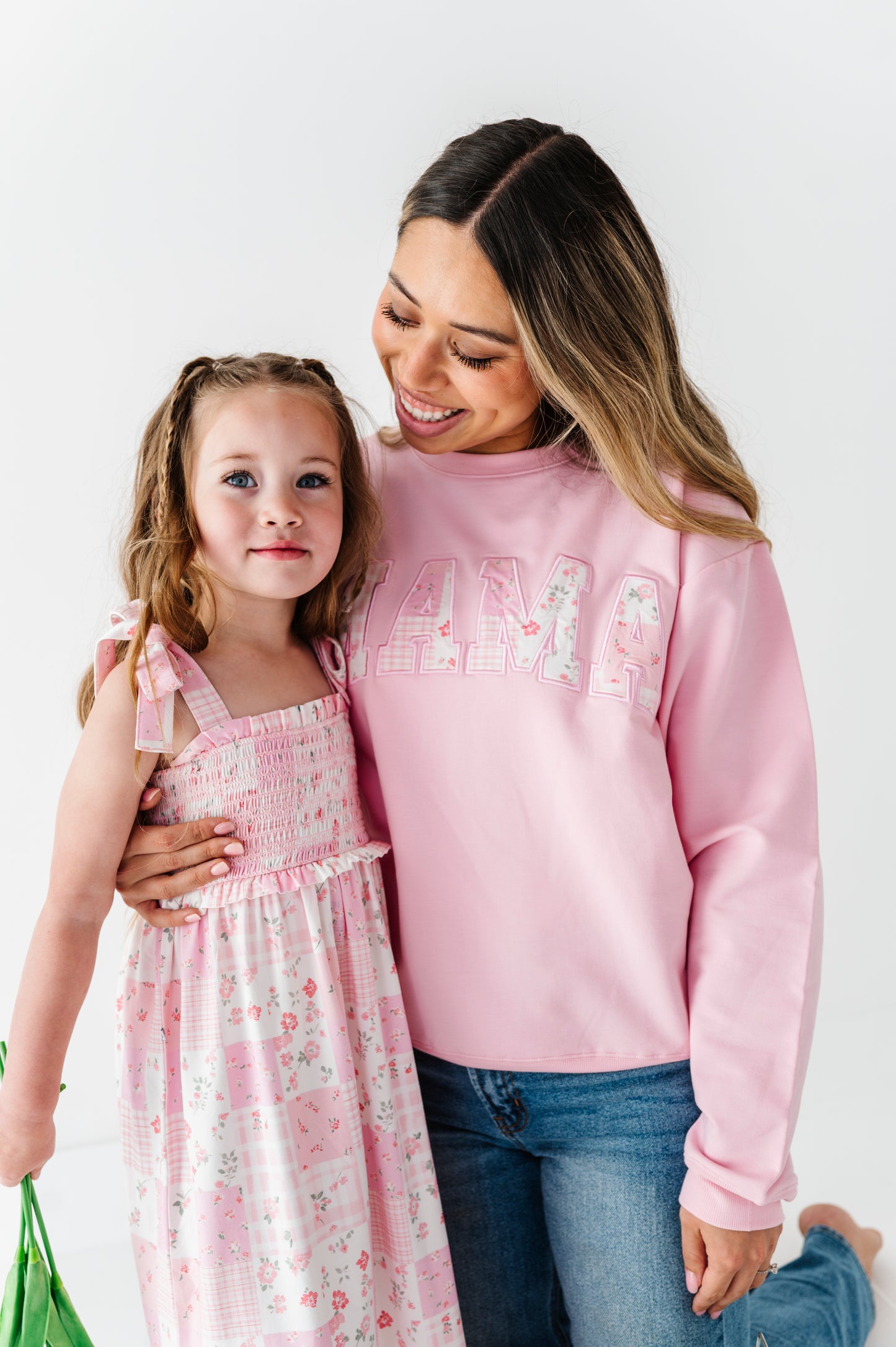 Woman wearing a bamboo sweatshirt that says "MAMA," with her arm wrapped around her daughter in a coordinating dress 