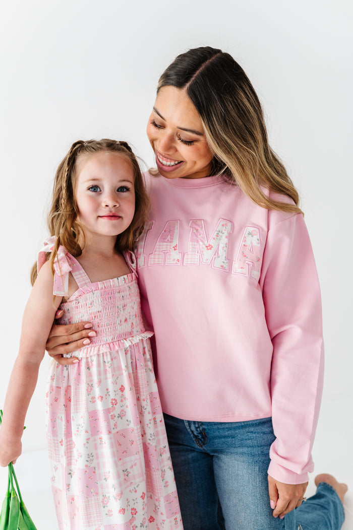 Woman wearing a bamboo sweatshirt that says "MAMA," with her arm wrapped around her daughter in a coordinating dress 