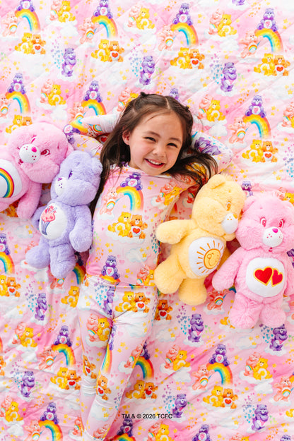Child holding Care Bears plush toys against a colorful Care Bears patterned background