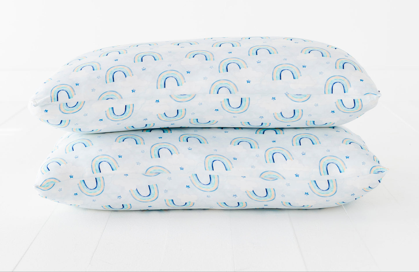 Two bamboo pillowcases with a blue watercolor rainbow pattern on a white background
