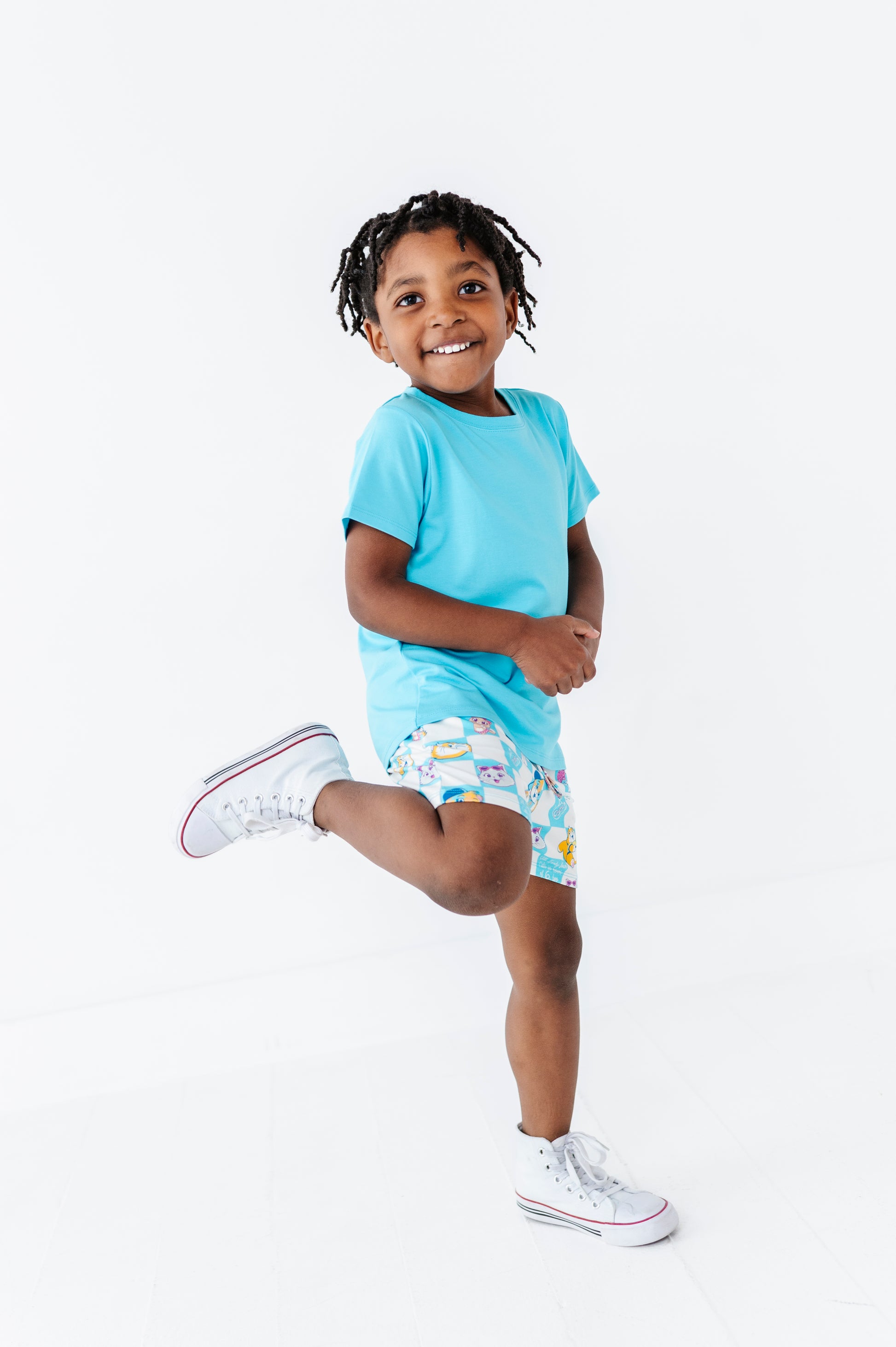 Child wearing a light blue bamboo blend t-shirt and patterned 44 Cats bamboo shorts on a white background