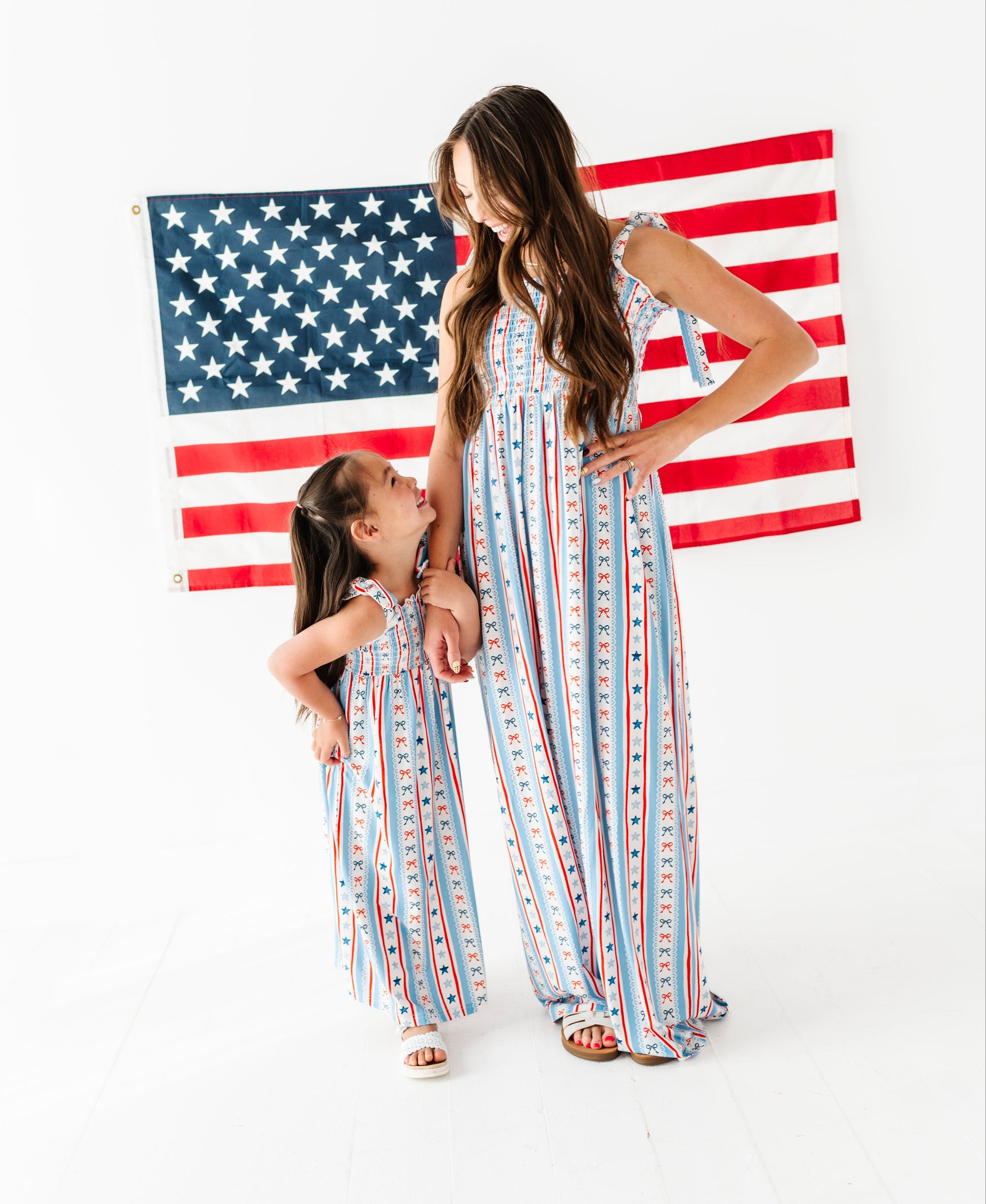 Two women in matching striped bamboo-cotton maxi dresses standing in front of an American flag.