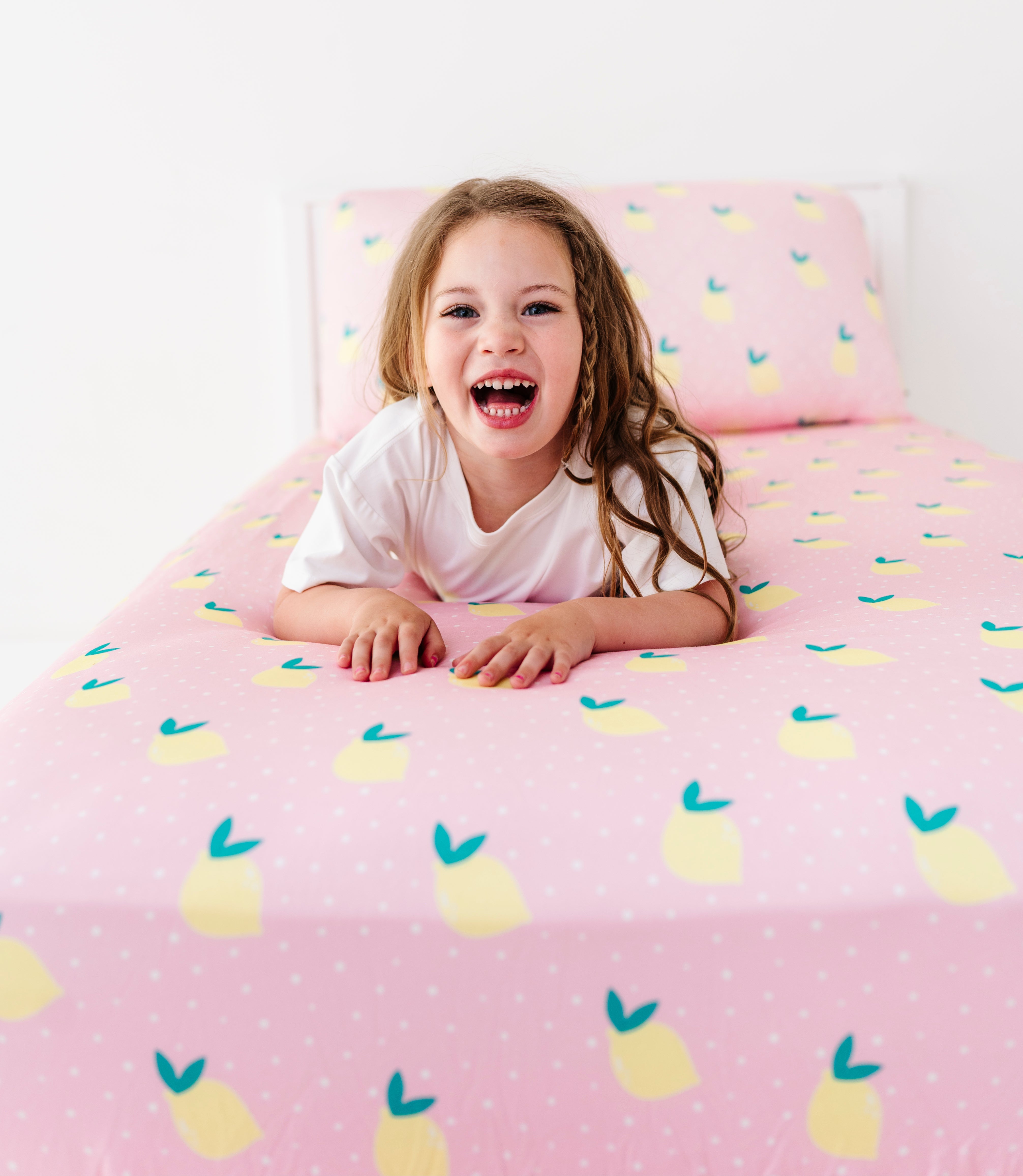Child lying on a bed with pink lemon-patterned bedding