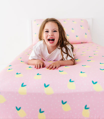 Child lying on a bed with pink lemon-patterned bedding