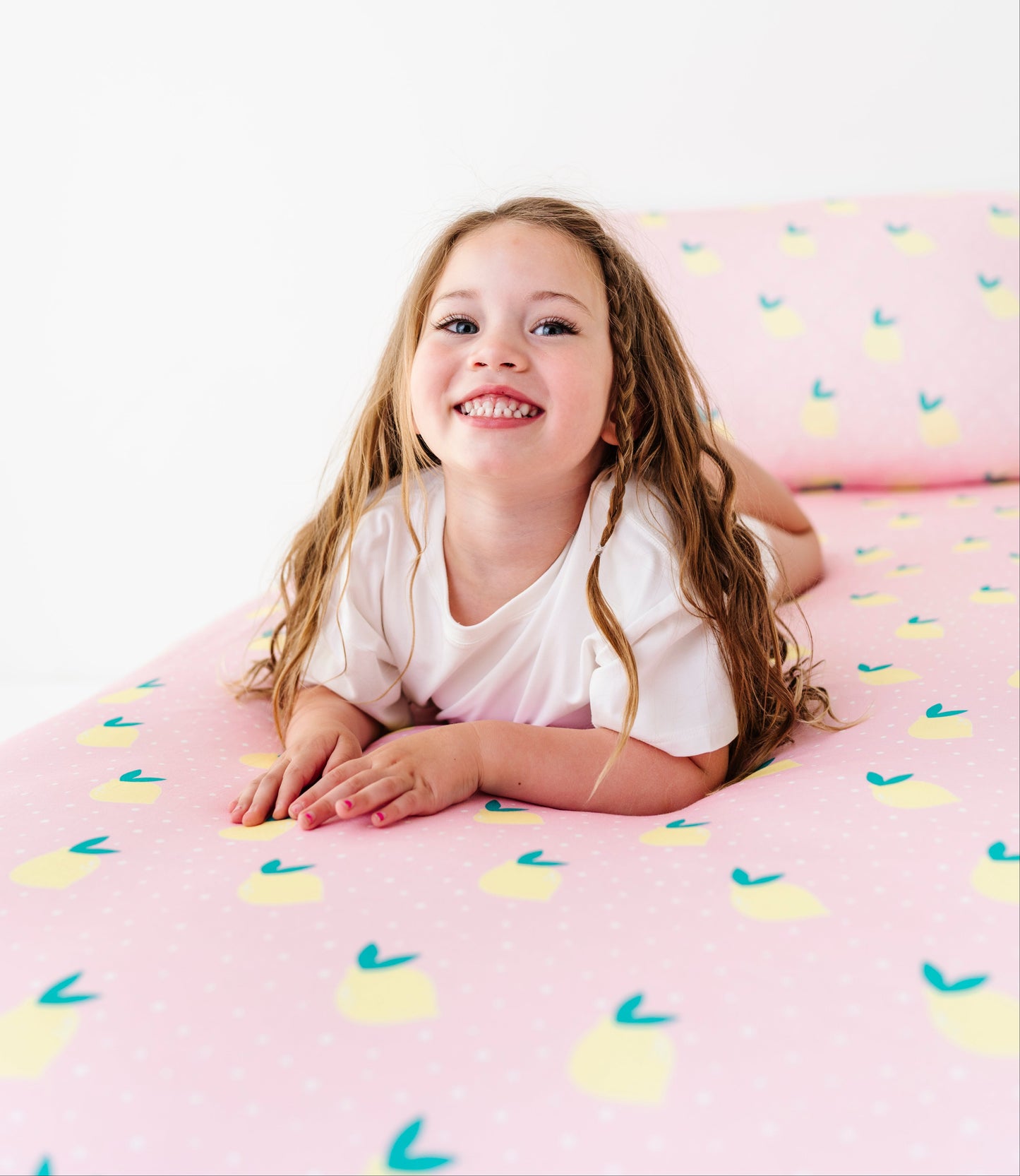 Young girl lying on a pink sheet with lemon pattern