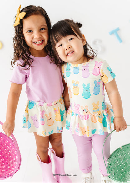 Two young girls wearing colorful Peeps-themed outfits on a white background