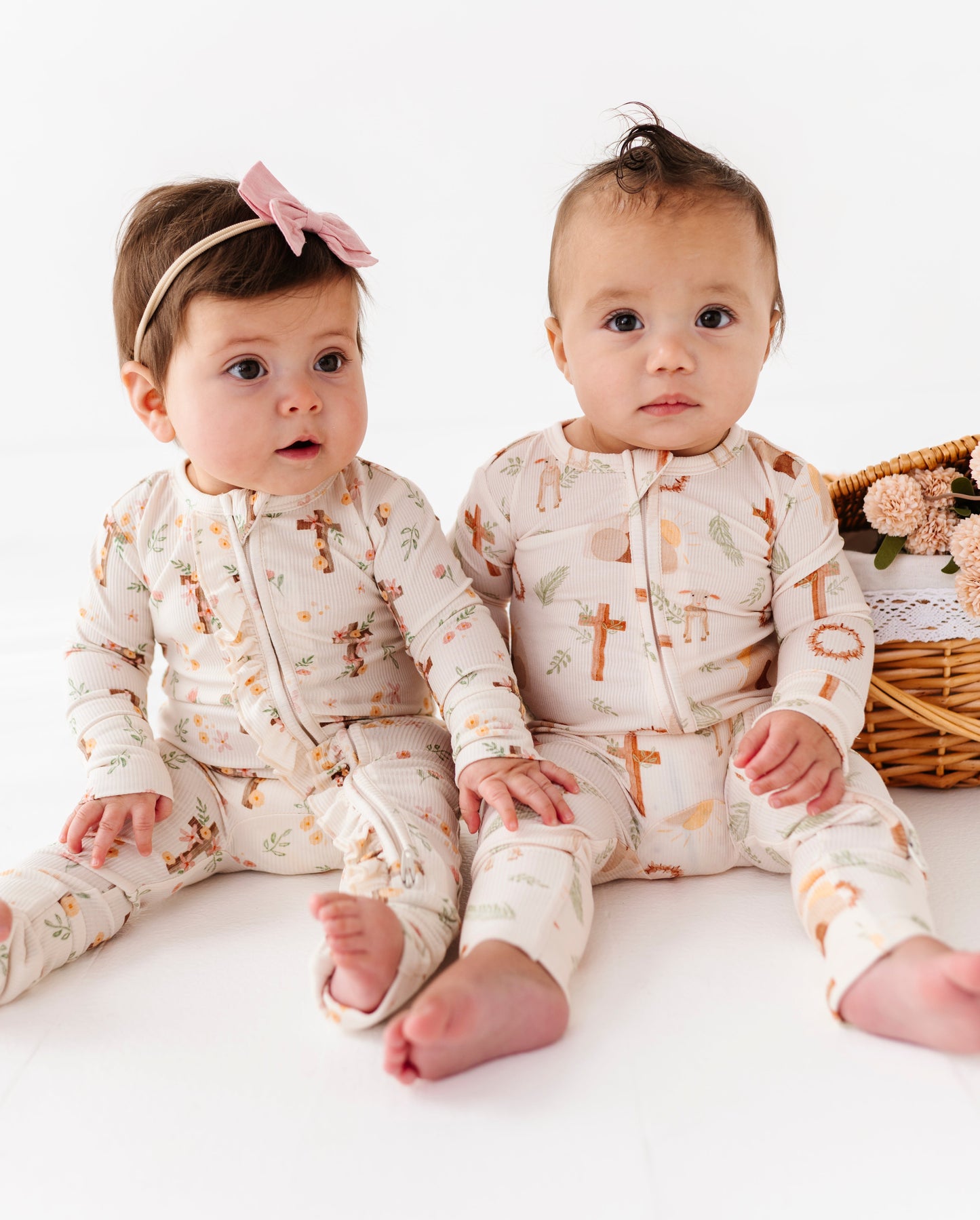 Two babies wearing matching ribbed bamboo pajamas with cross patterns on a white background