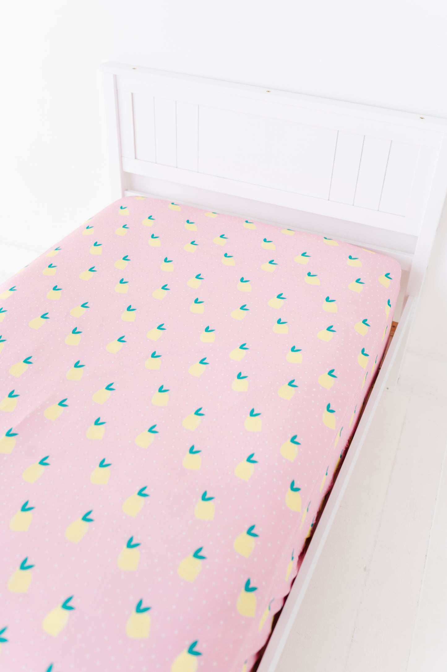 Pink twin sheet with lemon pattern on a white bed