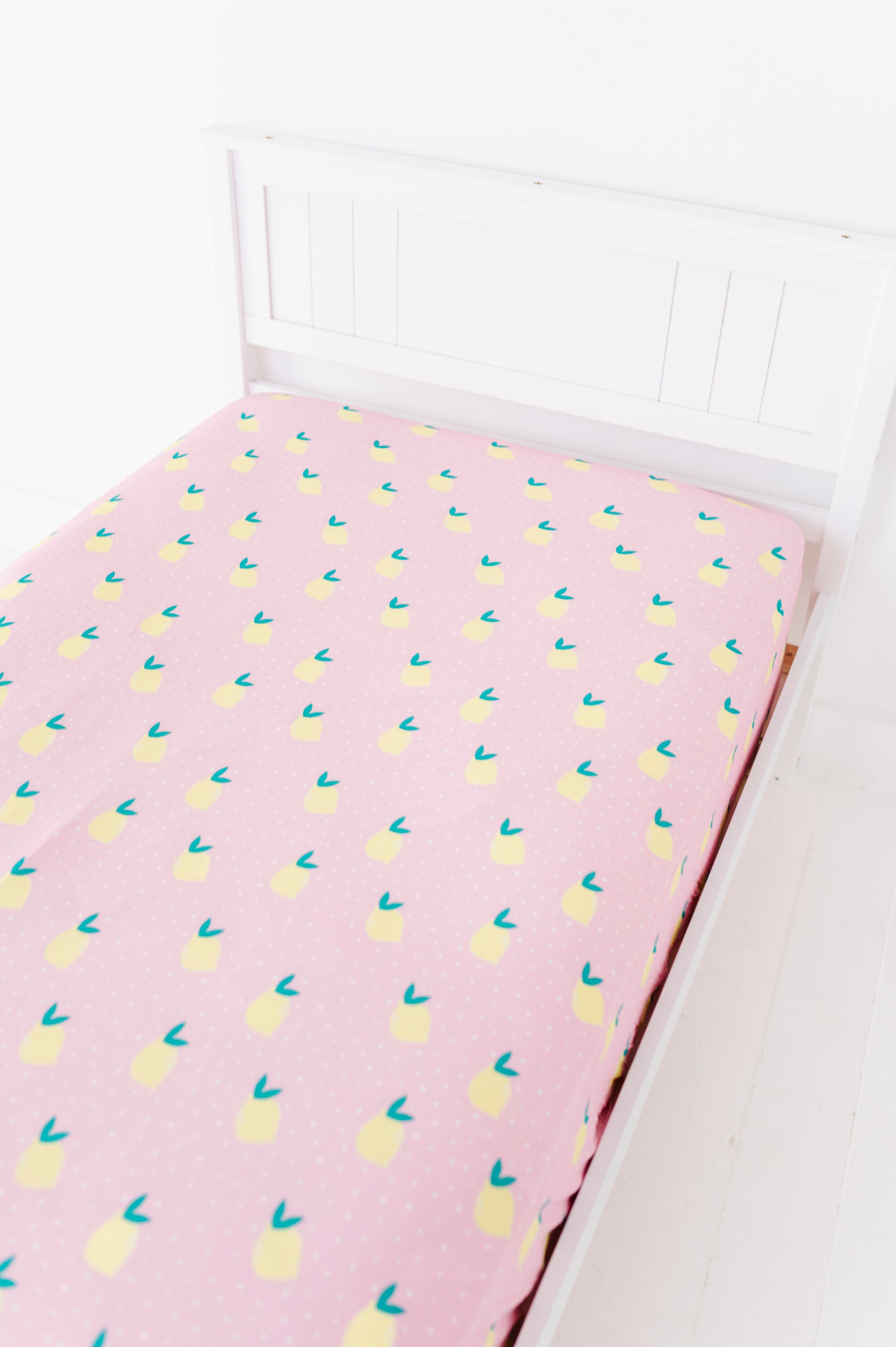 Pink twin sheet with lemon pattern on a white bed