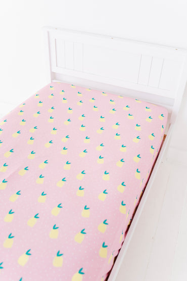 Pink twin sheet with lemon pattern on a white bed