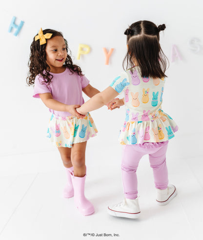 Two young girls in matching outfits with colorful letter decorations on a white background