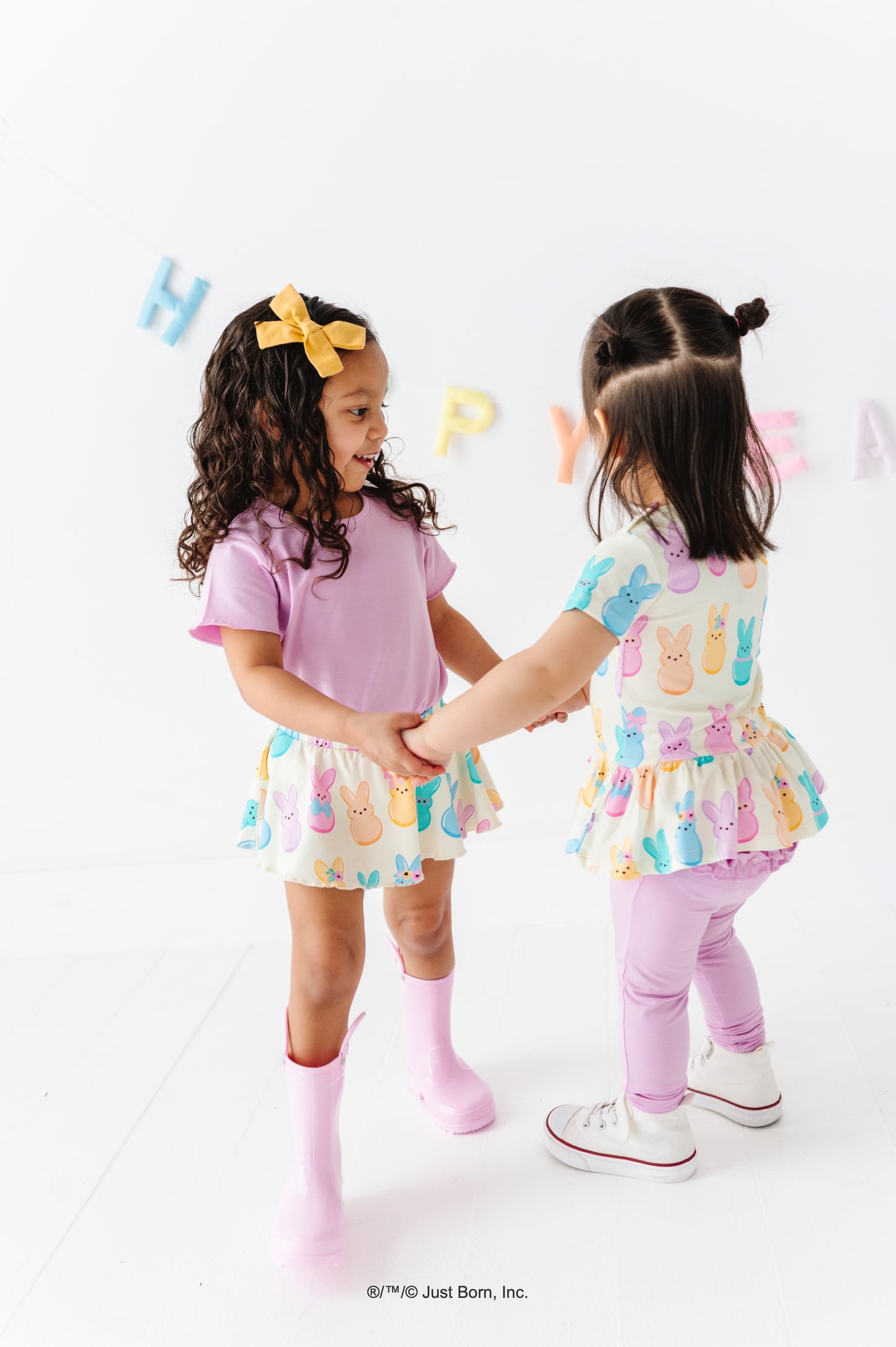 Two young girls in colorful PEEPS® outfits standing on a white background