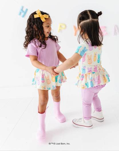 Two young girls in colorful outfits standing on a white background