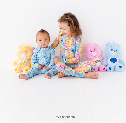 Toddler sitting in Care Bears™ Stare bamboo pajamas styled with matching Care Bears plush toys