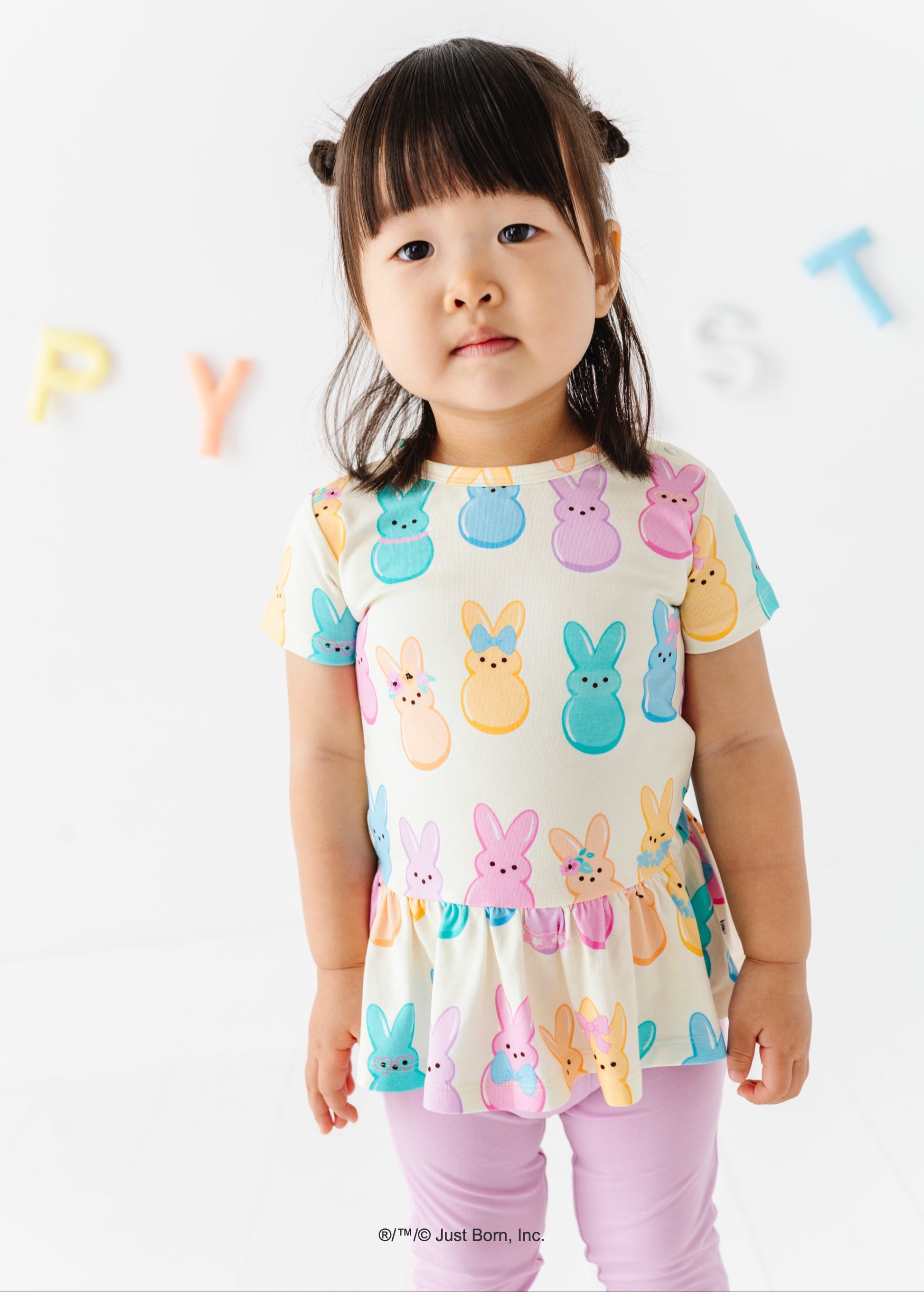 Child wearing a colorful Peeps-themed top with a plain background