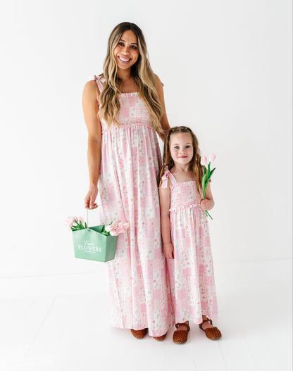 Woman and child in matching pink floral bamboo dresses holding flowers on a white background