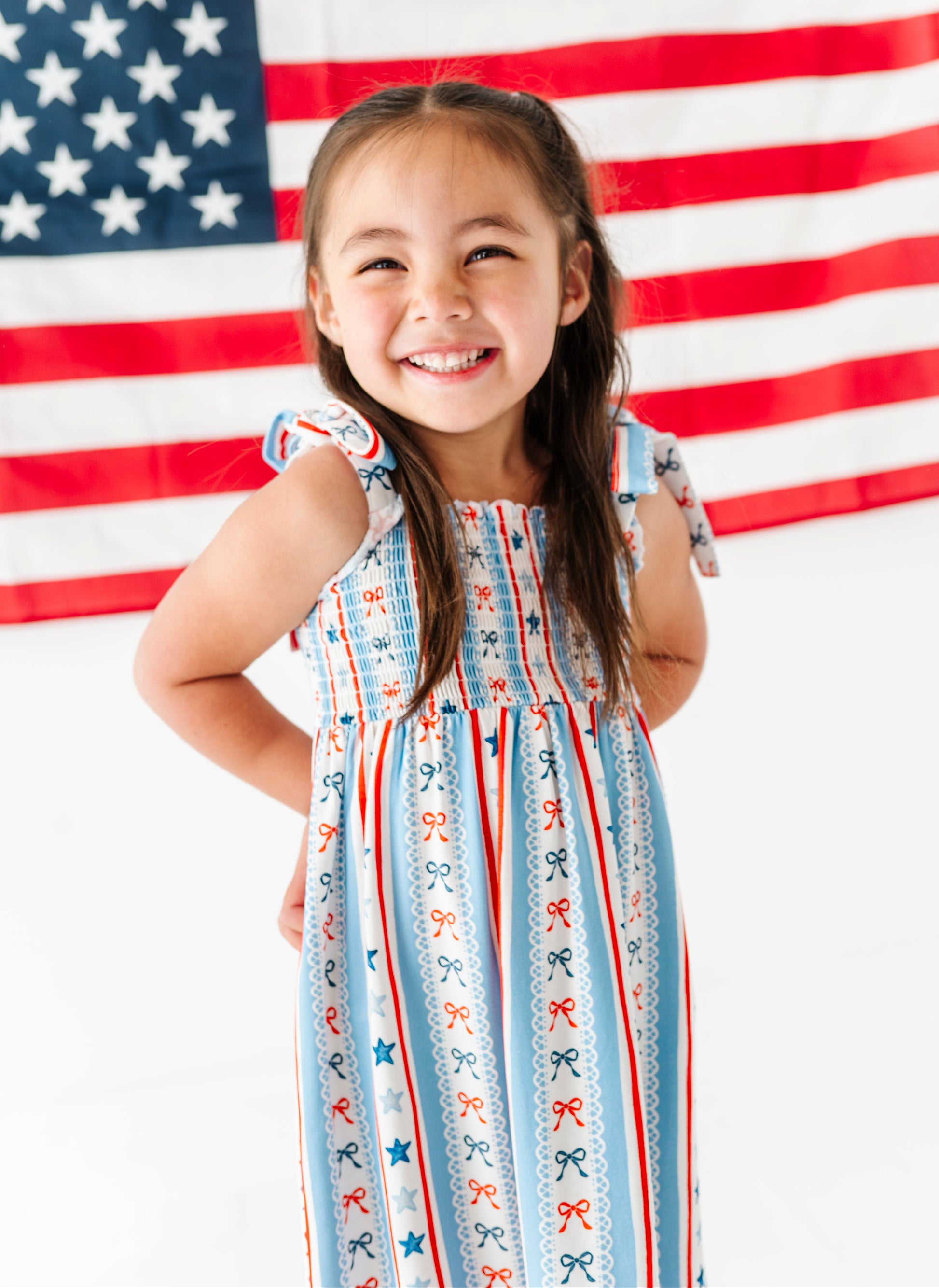 Child in a patriotic dress standing in front of an American flag