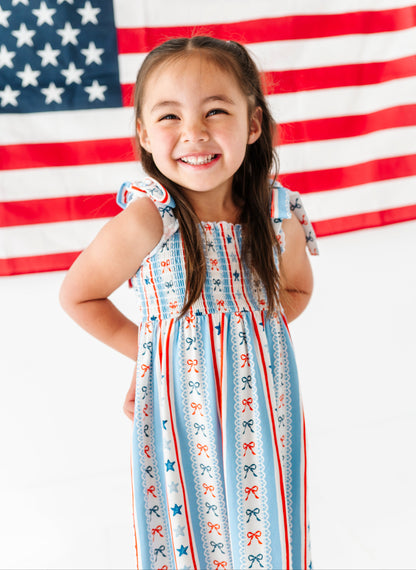 Child in a patriotic dress standing in front of an American flag
