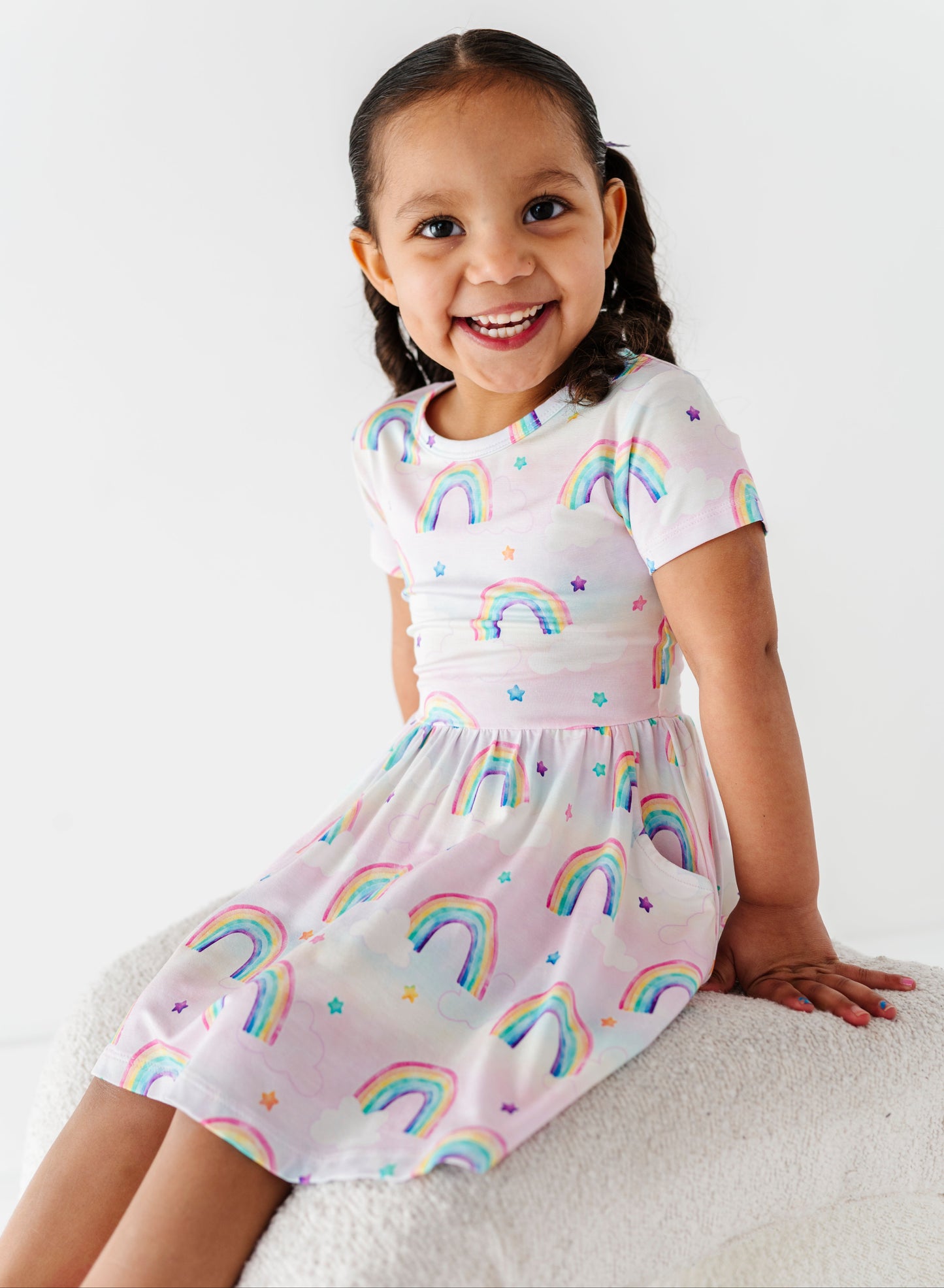 Young girl wearing a bamboo dress with watercolor rainbow patterns on a white background