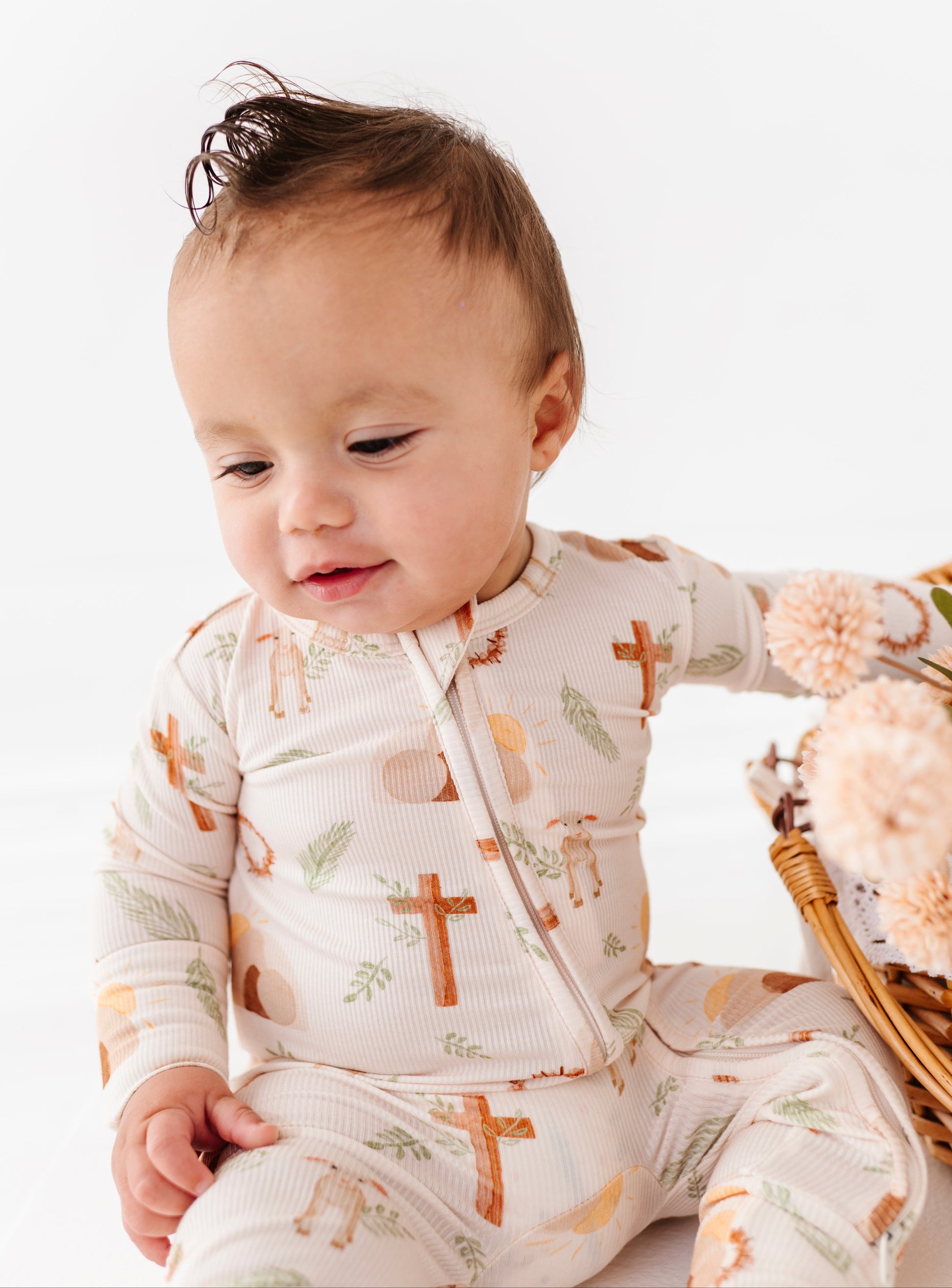 Baby wearing a bamboo convertible romper with cross patterns on a white background