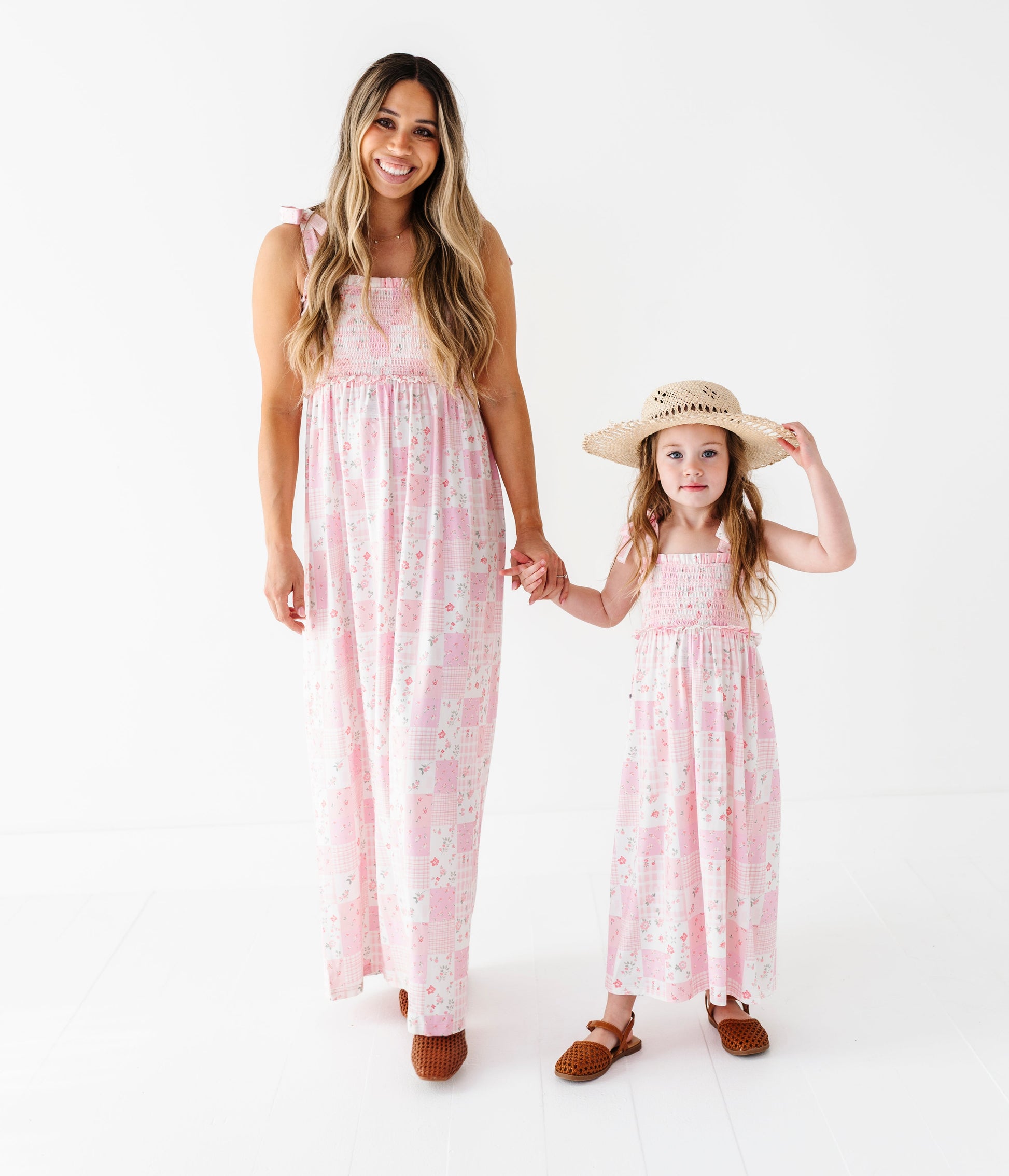 Woman and young girl wearing matching pink floral bamboo maxi dresses on a white background