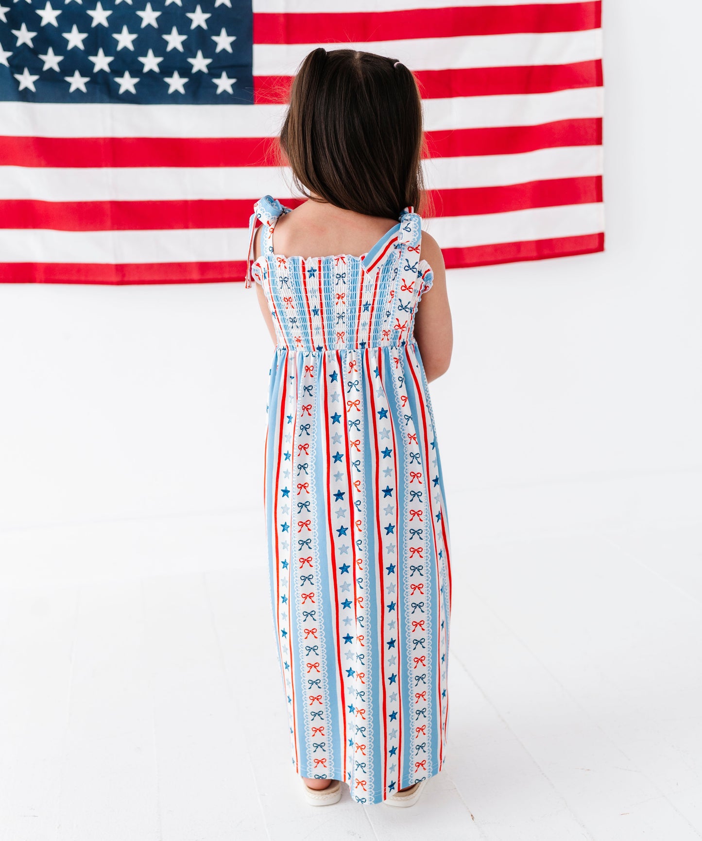 Person wearing a dress with American flag pattern in front of an American flag