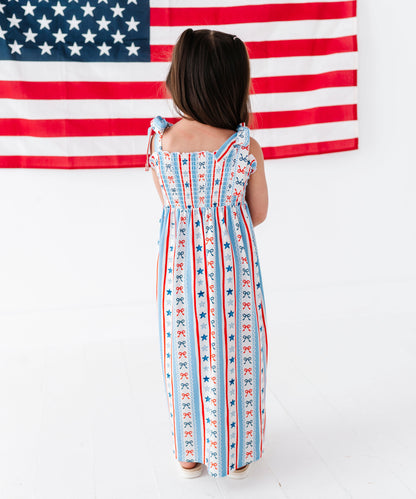 Person wearing a dress with American flag pattern in front of an American flag