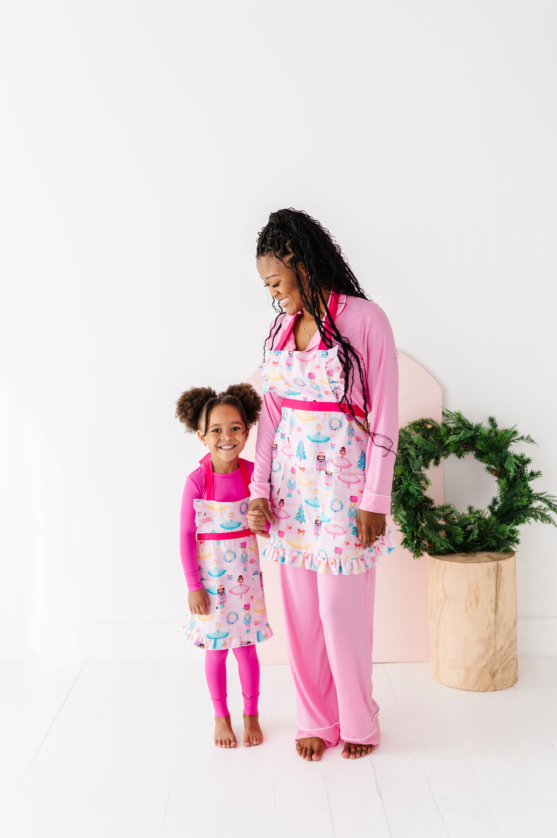 Woman and child wearing matching Sugarplum holiday baking aprons in kitchen setting