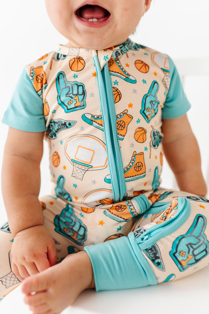 Baby wearing a colorful onesie with sports-themed design on a white background