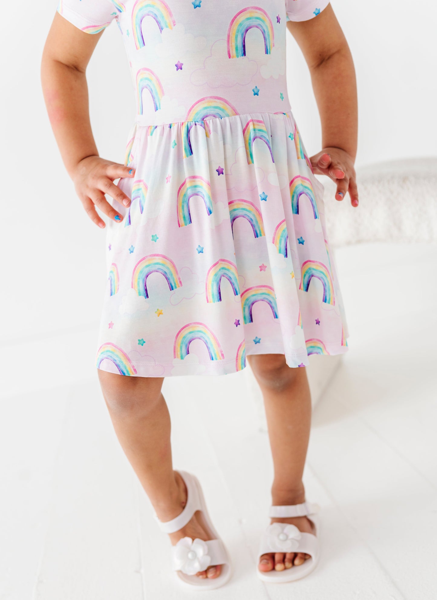 Child wearing a bamboo dress with watercolor rainbow pattern on a white background