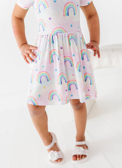 Child wearing a bamboo dress with watercolor rainbow pattern on a white background