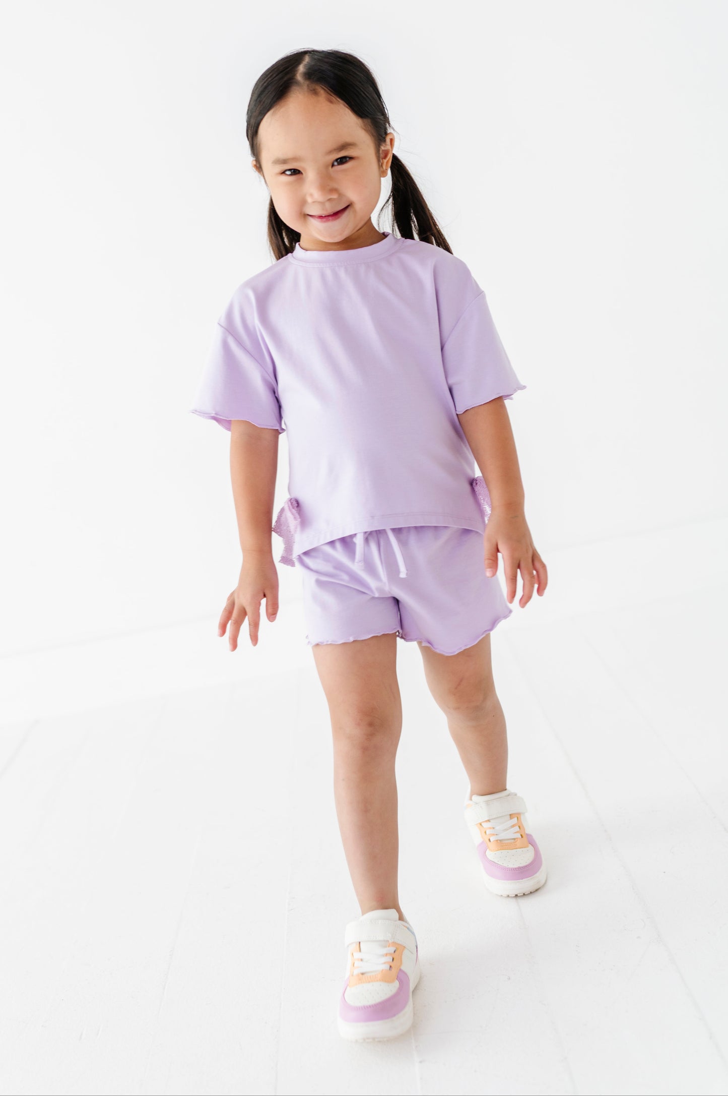 Young girl wearing a purple outfit on a white background