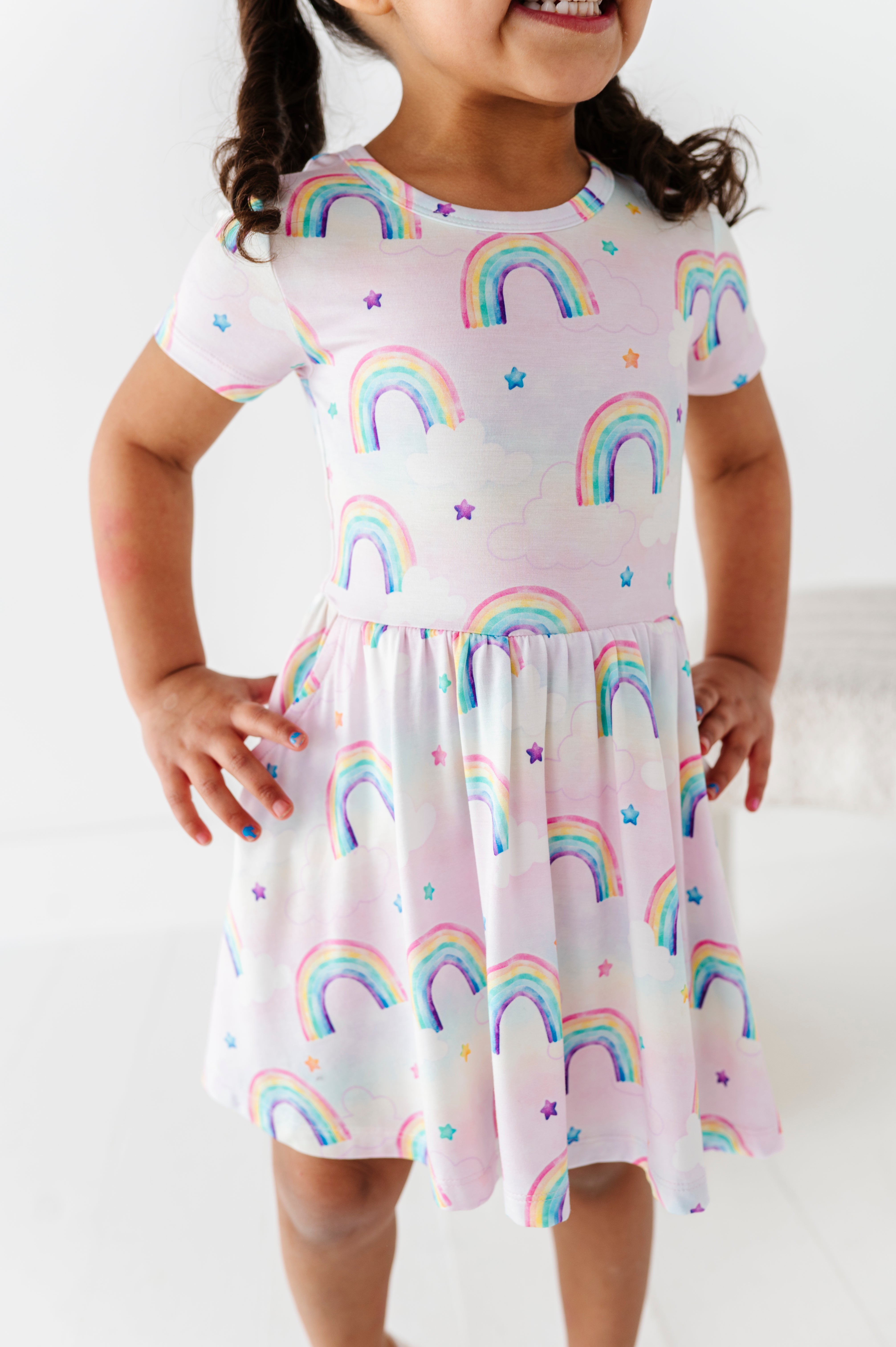 Child wearing a bamboo dress with watercolor rainbow patterns on a white background