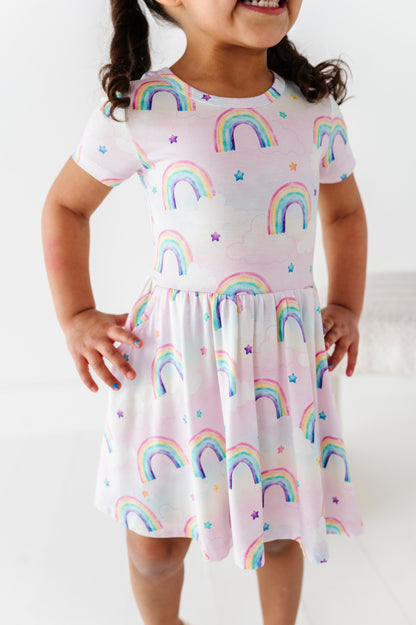Child wearing a bamboo dress with watercolor rainbow patterns on a white background