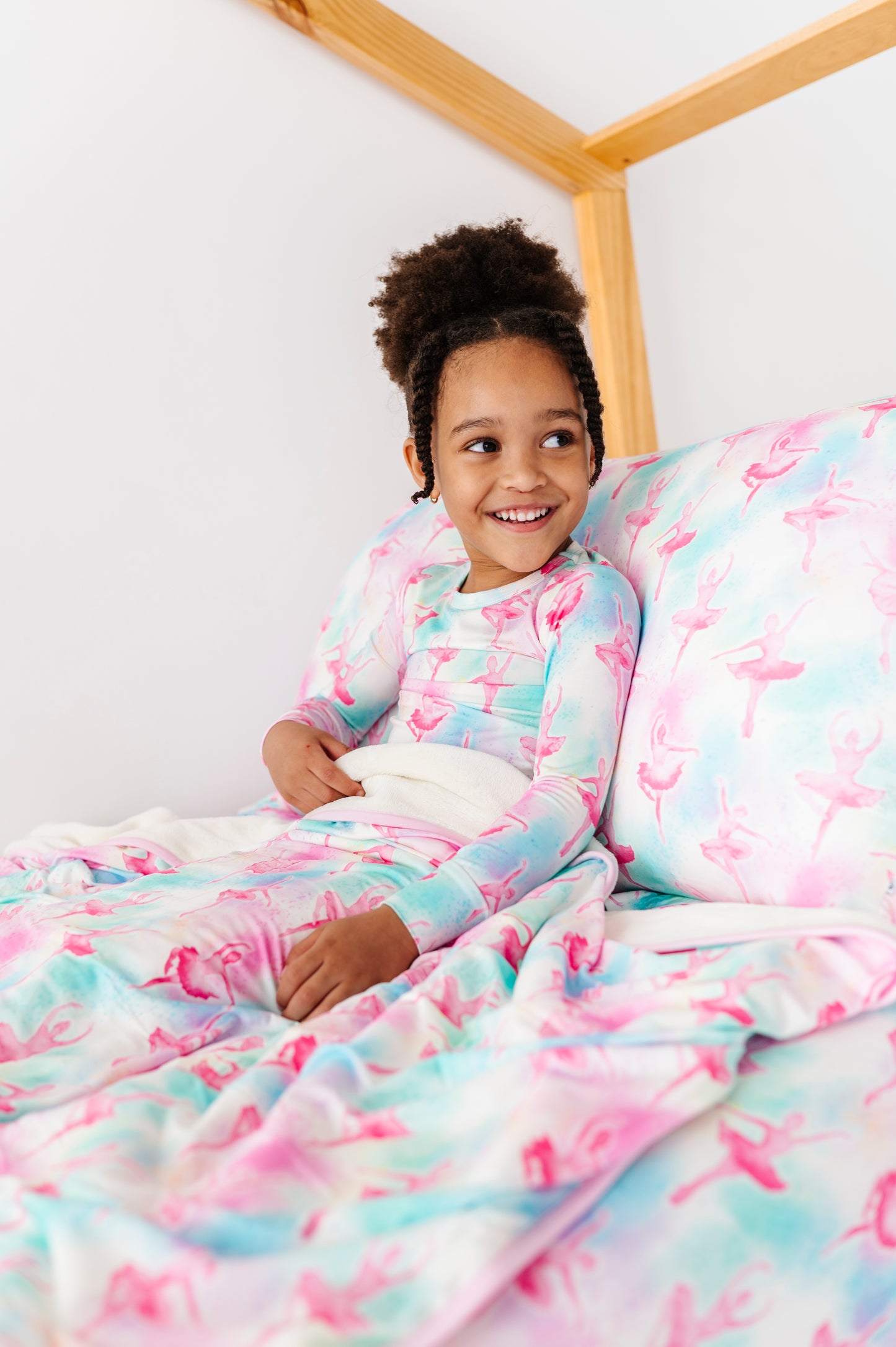 Child lying on a bed with colorful ballet-themed bamboo bedding 