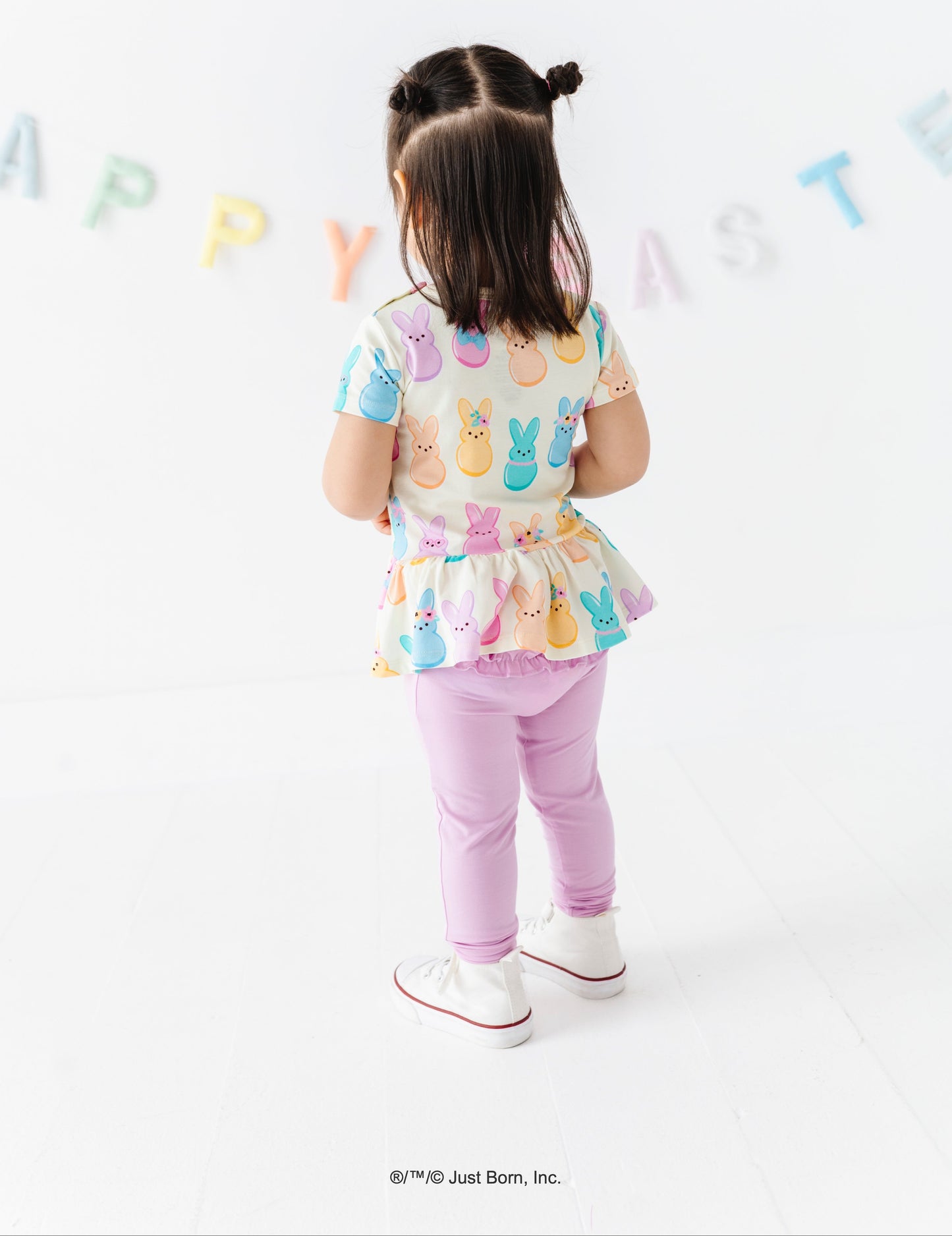 Child wearing a colorful PEEPS®  bunny-themed outfit with a white background