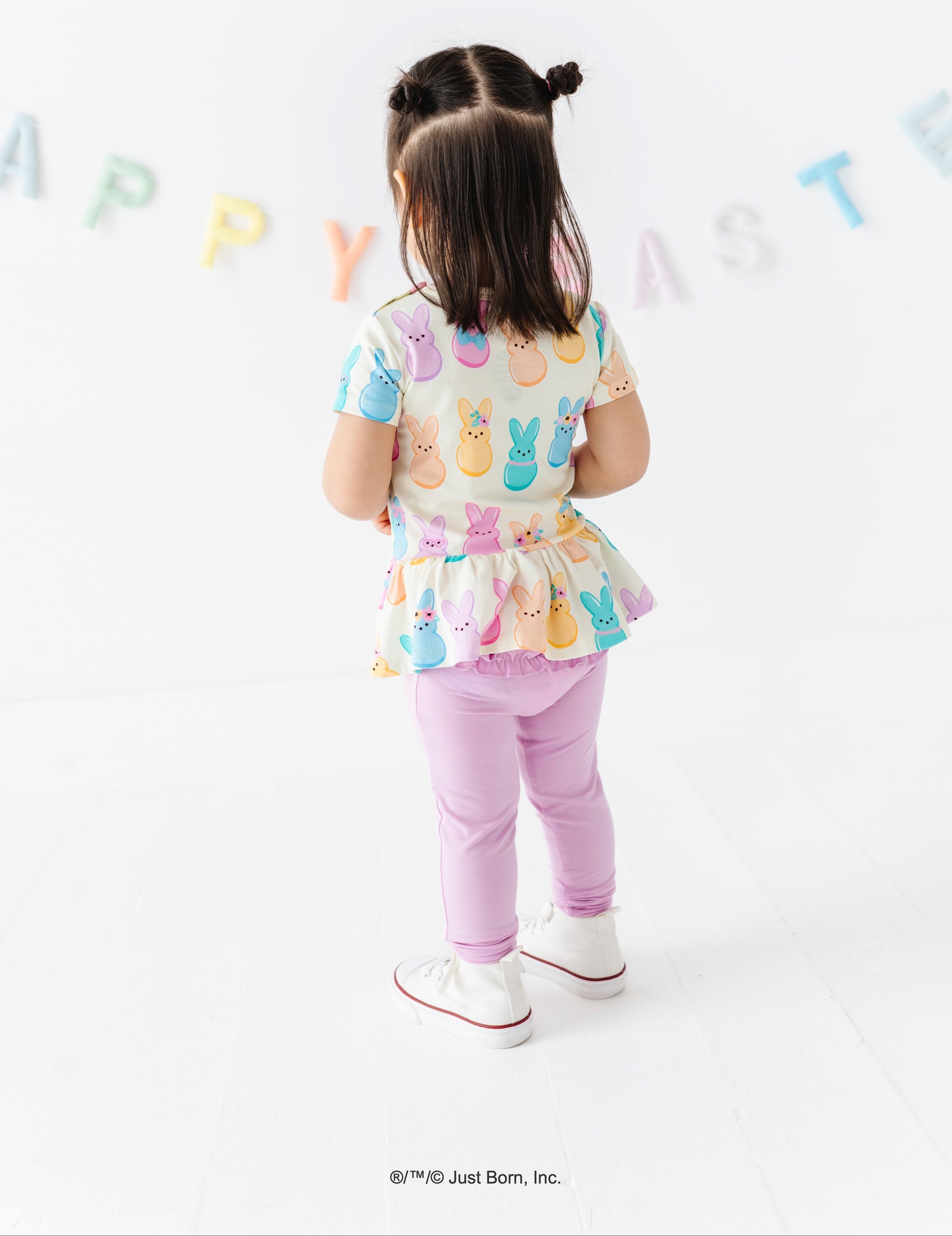 Child wearing a colorful PEEPS®  bunny-themed outfit with a white background