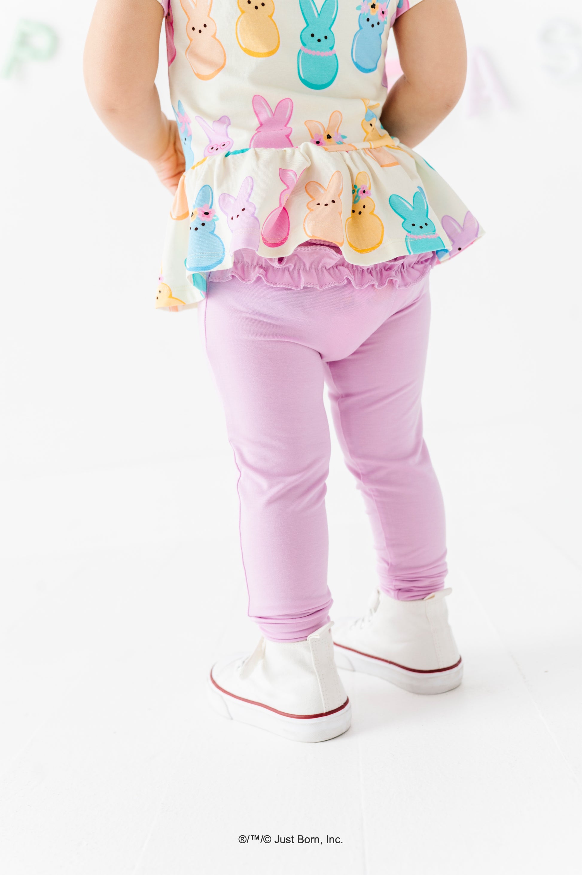 Child wearing a colorful PEEPS® top and lavender leggings on a white background