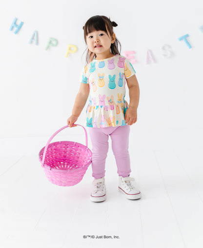 Child wearing a colorful shirt with PEEPS®  bunny designs, holding a pink Easter basket, on a white background with 'Happy Easter' text.
