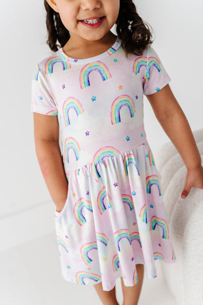 Child wearing a bamboo dress with watercolor rainbow patterns on a white background