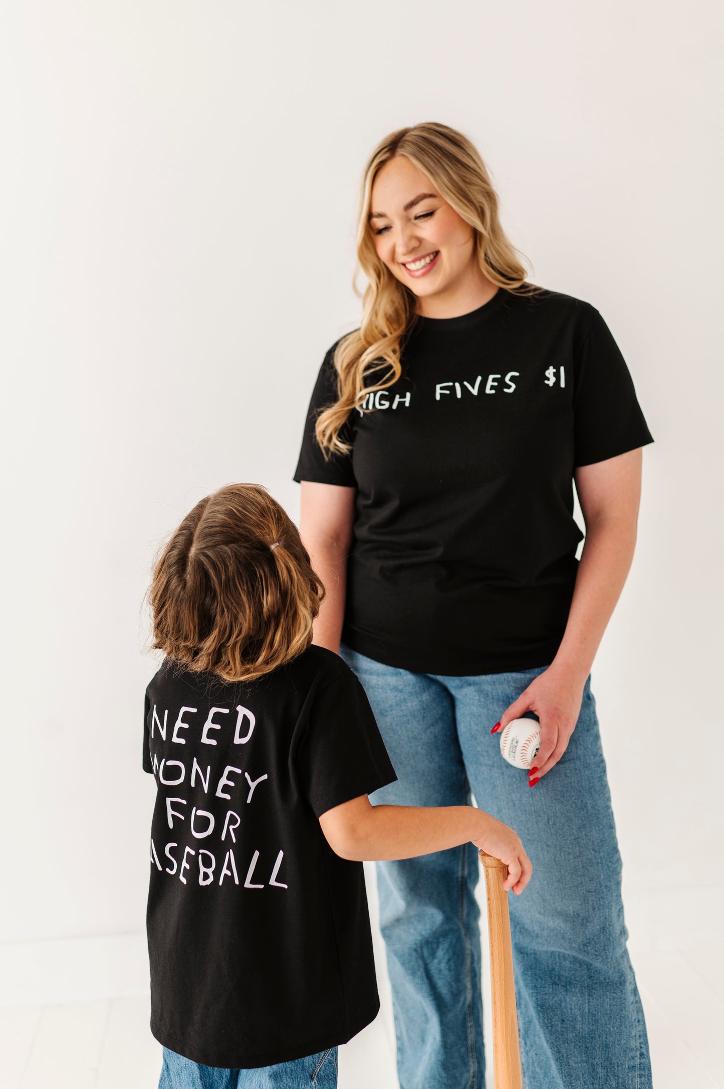 Two people wearing black t-shirts with baseball text, standing against a white background.
