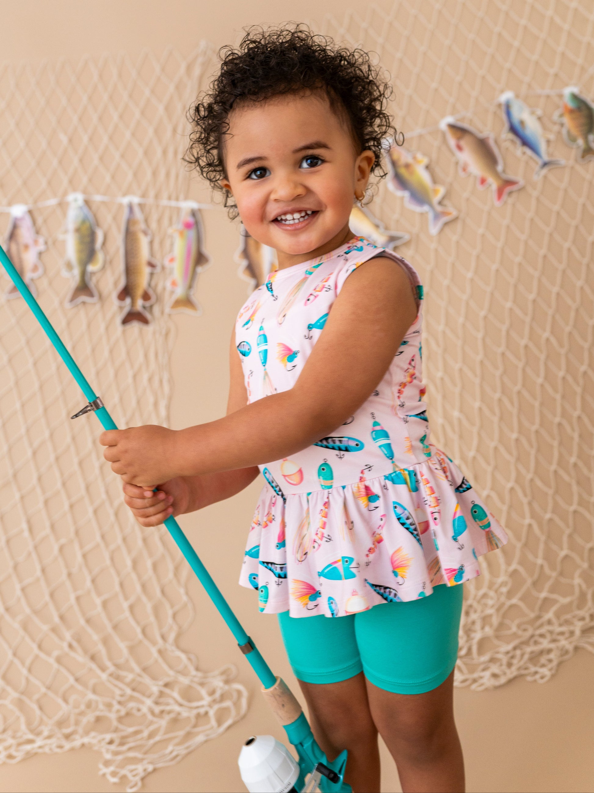 Child holding a fishing rod with a fish-themed background
