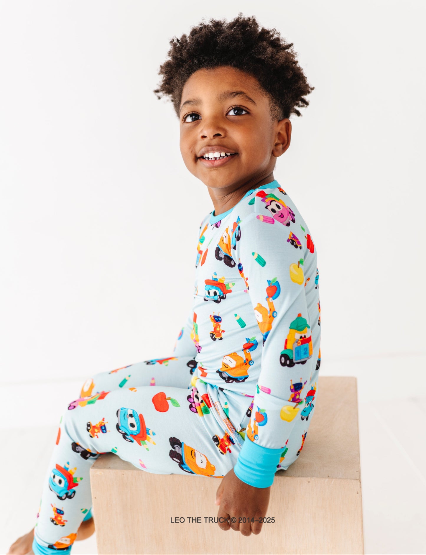 Child wearing a colorful Leo the Truck bamboo two-piece set on a white background