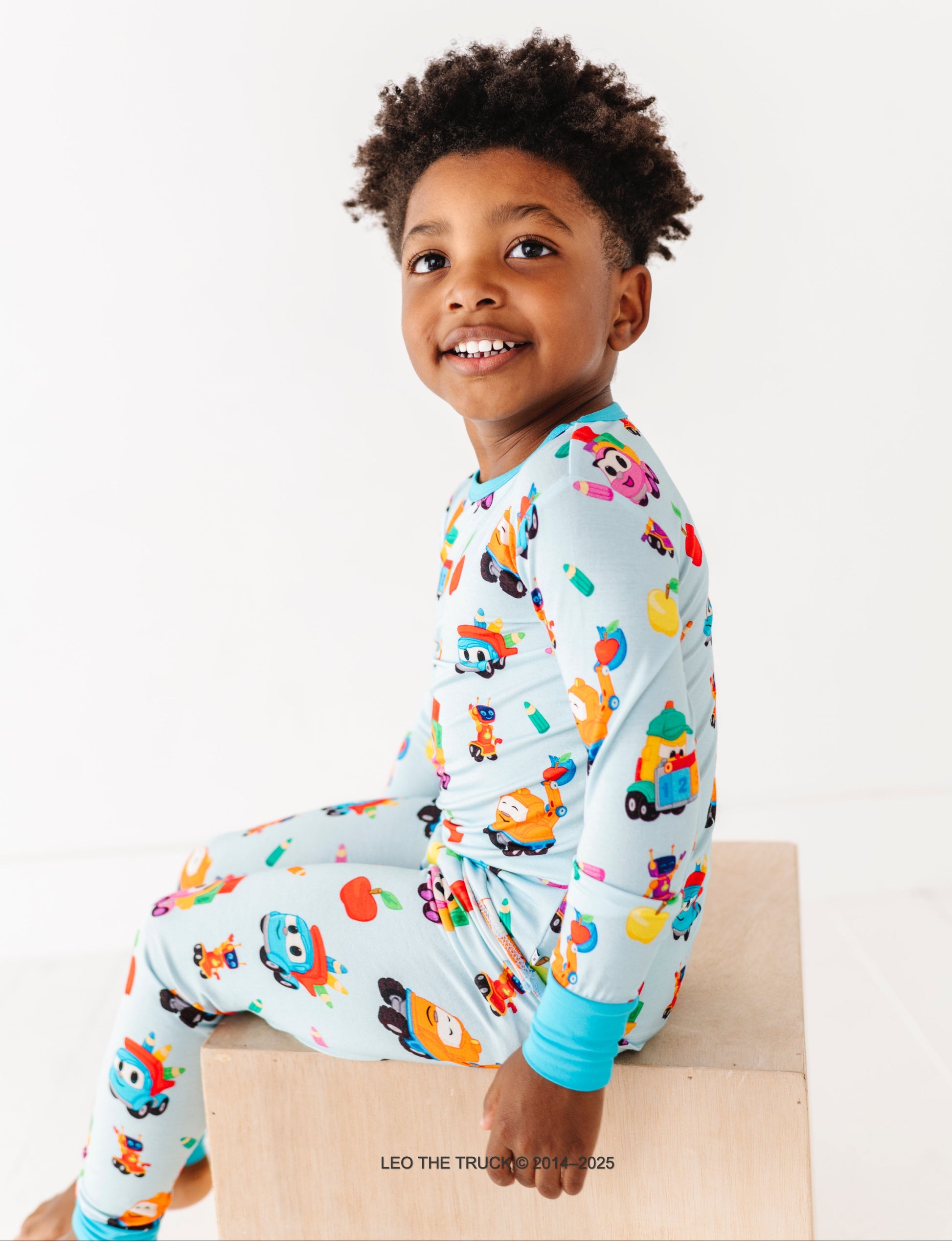 Child wearing a colorful Leo the Truck bamboo two-piece set on a white background