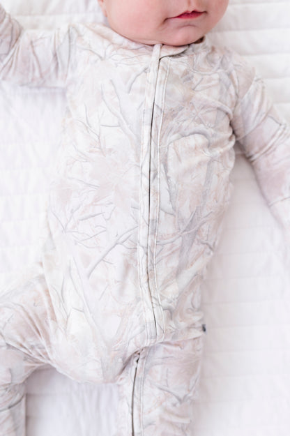 Baby wearing a tree camo romper on a white background
