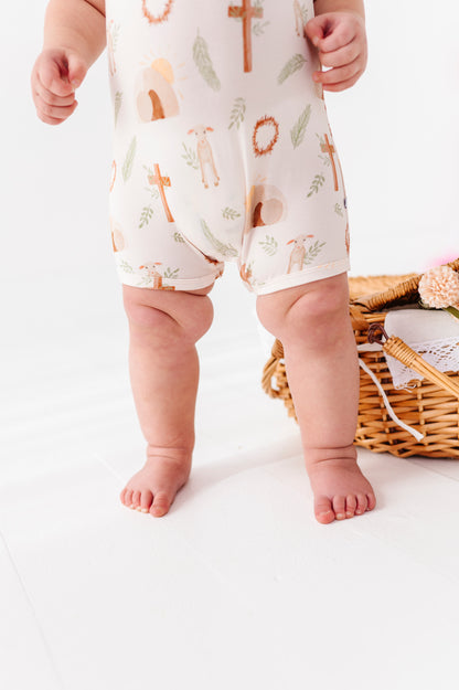 Close-up of a baby wearing a bamboo Christian romper with Easter print on a white background