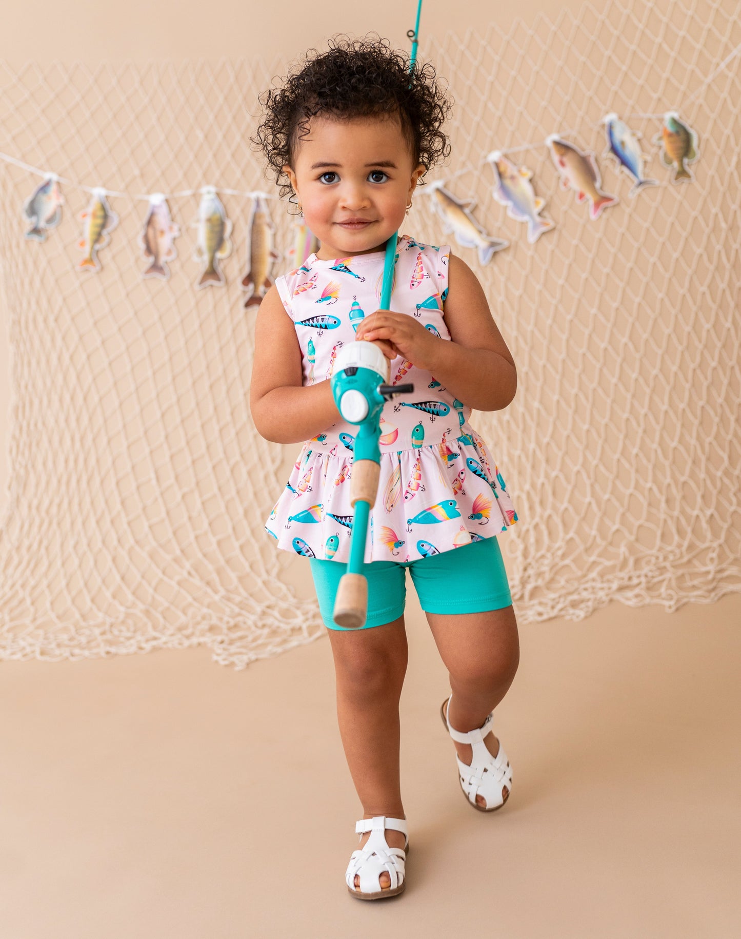 Child holding a fishing rod with a fish-themed backdrop